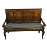 A George III oak settle, with four fielded panels to the back, rope strung with padded seat squab,