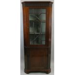 A mahogany corner cupboard, the upper section with an astragal glazed door, over a cupboard door,
