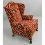 An upholstered wing armchair, raised on hairy lions paw feet, 82 cm wide.