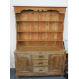 A pine dresser, the base compromising of central three drawers with cupboard either side,