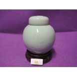 A ginger jar and stand with a Korean style green glaze and design