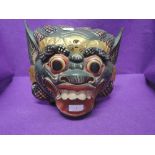 A hand carved and decorated wooden Chinese mask in a Tibetan style possibly of a demon or dragon