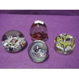 Four glass paper weights with various colours and design styles