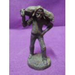 A bronze cast figure of a farm worker with animal feed sack