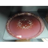 A cranberry glass tray with hand decorated flower design