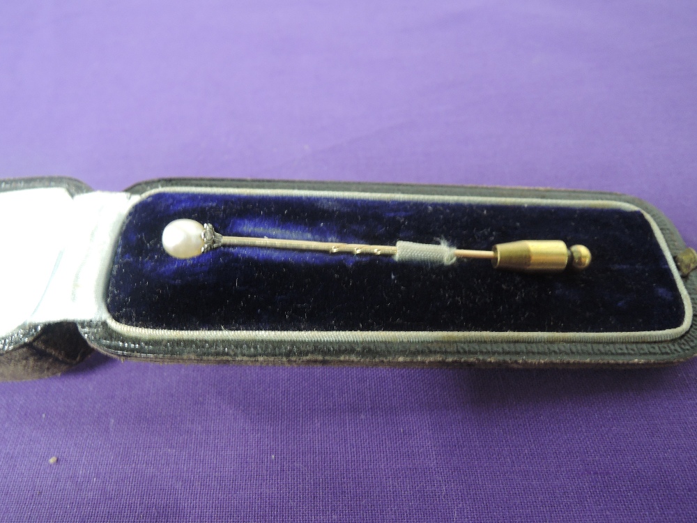 A cased cultured pearl stick pin on a diamond chip set crown mount to yellow metal pin, no marks