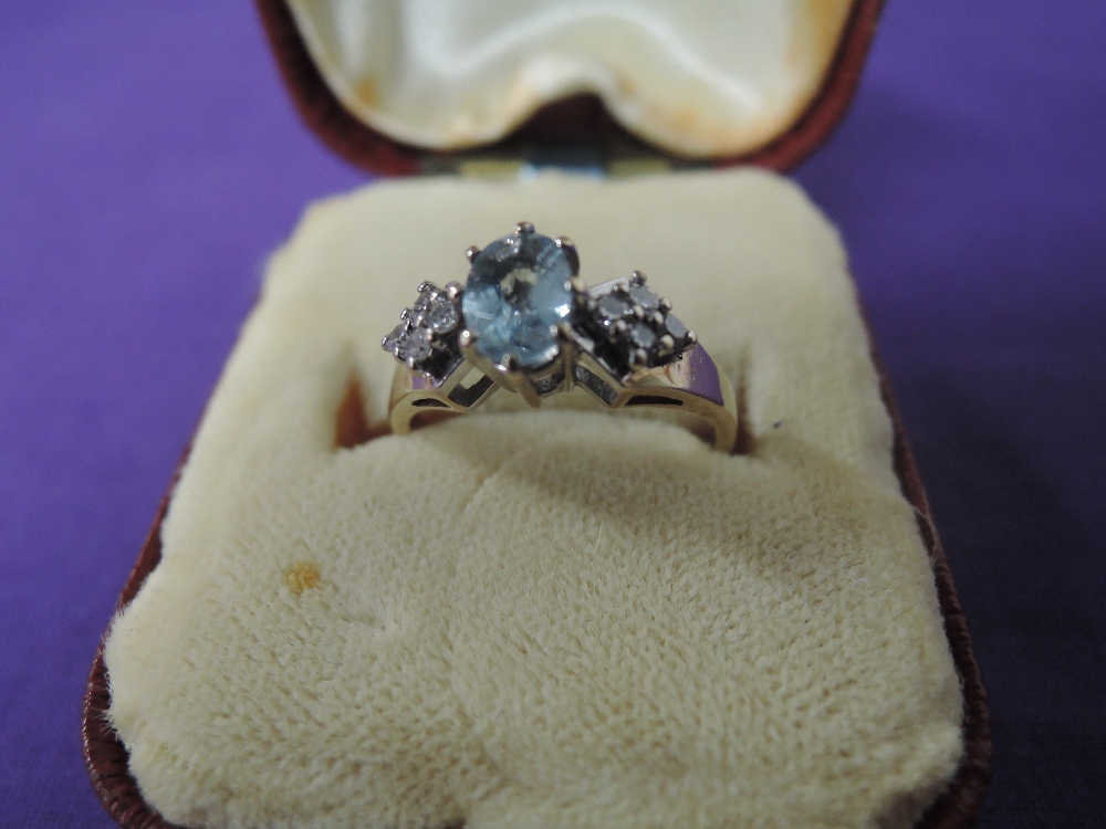 A lady's dress ring having a central oval blue topaz flanked by cubic zirconia on a 9ct gold loop,