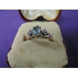 A lady's dress ring having a central oval blue topaz flanked by cubic zirconia on a 9ct gold loop,