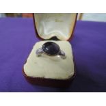 A lady's dress ring having an oval amethyst style stone on a white metal loop