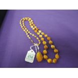 A Baltic amber rough cut pendant and amber coloured glass bead necklace