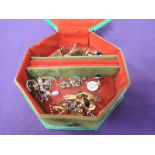 A green travel jewellery case containing a small selection of earrings, cufflinks etc