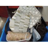 A box of vintage handbags in a mix of decades styles and eras. including straw, suede and fabric.
