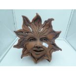 A terracotta plant or similar stand in a green man style design