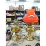 Two brass bodied oil lamps one with red glass shade