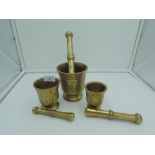 A set of graduated brass cast mortar and pestle with floral designs