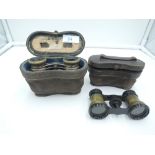 A pair of opera glasses of two tone Niello style in fitted case and another pair of opera glasses in