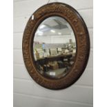 A hallway mirror with oval design bevel edged glass and ornate gilt and plaster frame