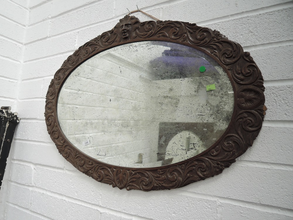 A late Victorian oak frame oval wall mirror having mask and foliate carved decoration