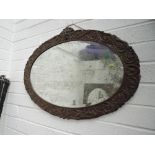 A late Victorian oak frame oval wall mirror having mask and foliate carved decoration