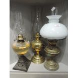 A selection of oil and paraffin lamps including pierced and decorated brass cast base and milk glass