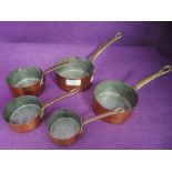 A set of graduated kitchen sauce pans with copper body and brass cast handles