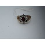 A lady's dress ring having a garnet and diamond cluster in an illusionary setting to decorative