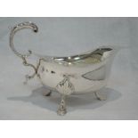 A large silver sauce boat having moulded loop handle, frilled rim and trefoil hoof feet, London