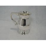 A silver tankard of plain baluster form having pedestal foot and flat topped moulded handle,