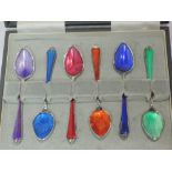 A cased set of six white metal coffee spoons having enamel guilloche decoration in bright colours,