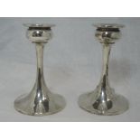 A pair of silver candlesticks having bulbous cups and tapered stems to weighted circular bases,