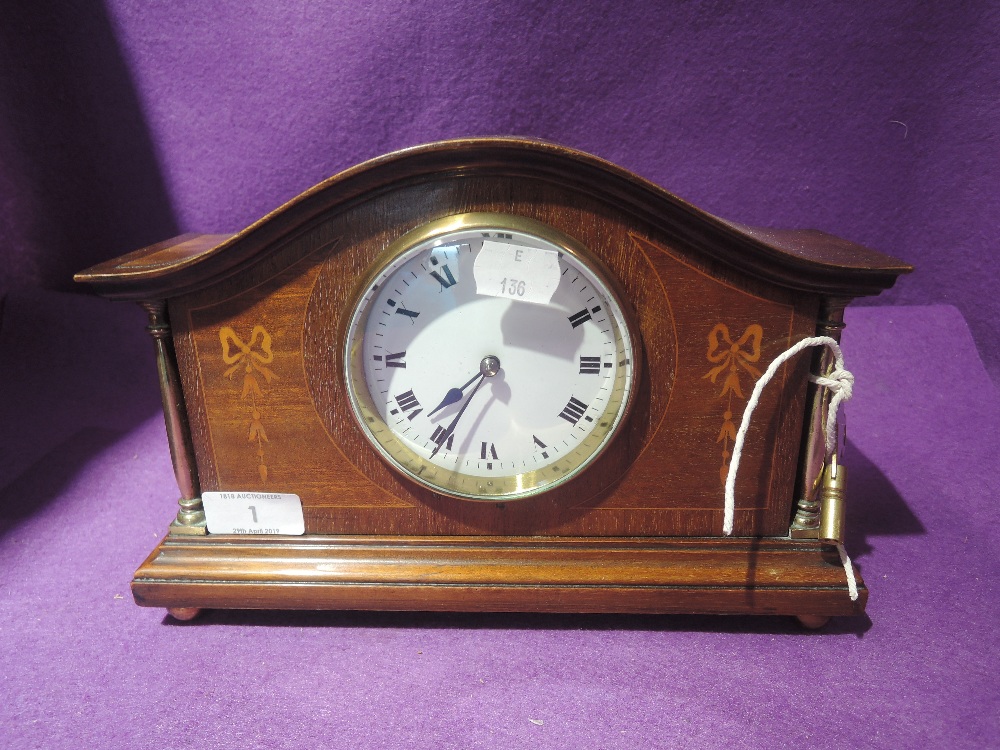 A mantle clock with veneer inlay frontage enamel face and brass column supports