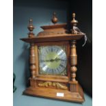 A bracket mounted clock with column design and brass face battery operated