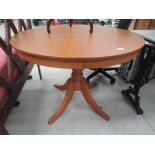 A modern teak effect circular dining table