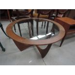 A vintage teak or sapele circular coffee table with glass top