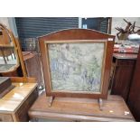A vintage stained frame fire screen having woolwork inset