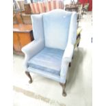 A traditional blue dralon wing back armchair