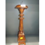 A wooden carved tall standing candle stick