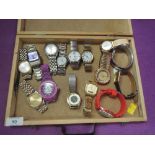 A wooden case containing 15 fashion wrist watches of various makes and designs