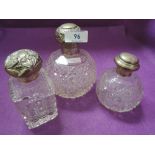 Two cut glass spherical perfume bottles and a similar cut glass rectangular bottle, all having HM