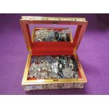 A small material jewellery box containing a selection of religious jewellery including rosary beads