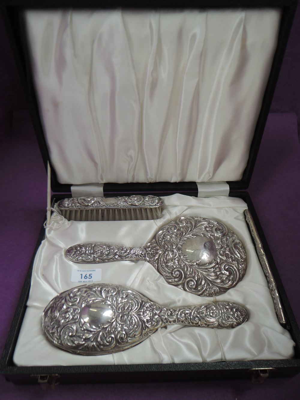 A cased HM silver four piece dressing table set having moulded mask and scroll decoration (af)