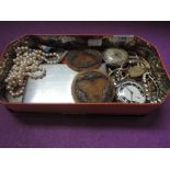 A vintage tin containing a selection of misc including two pocket watches, diamante, commemorative