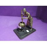 A brass cast ethnic figure of an African tribesman stirring cooking pot