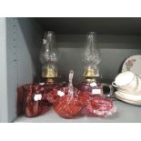A selection of cranberry glass wares including oil lamp pair