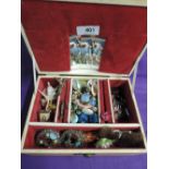 A vintage jewellery box containing a selection of clip earrings and brooches including ceramic and