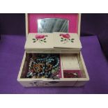 A retro painted wooden jewellery box containing a selection of costume jewellery including pin
