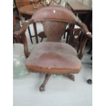 An antique officers style desk chair with leather seat