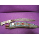 An early 20th century Kukri knife having bone handle with scabbard having white metal and bead