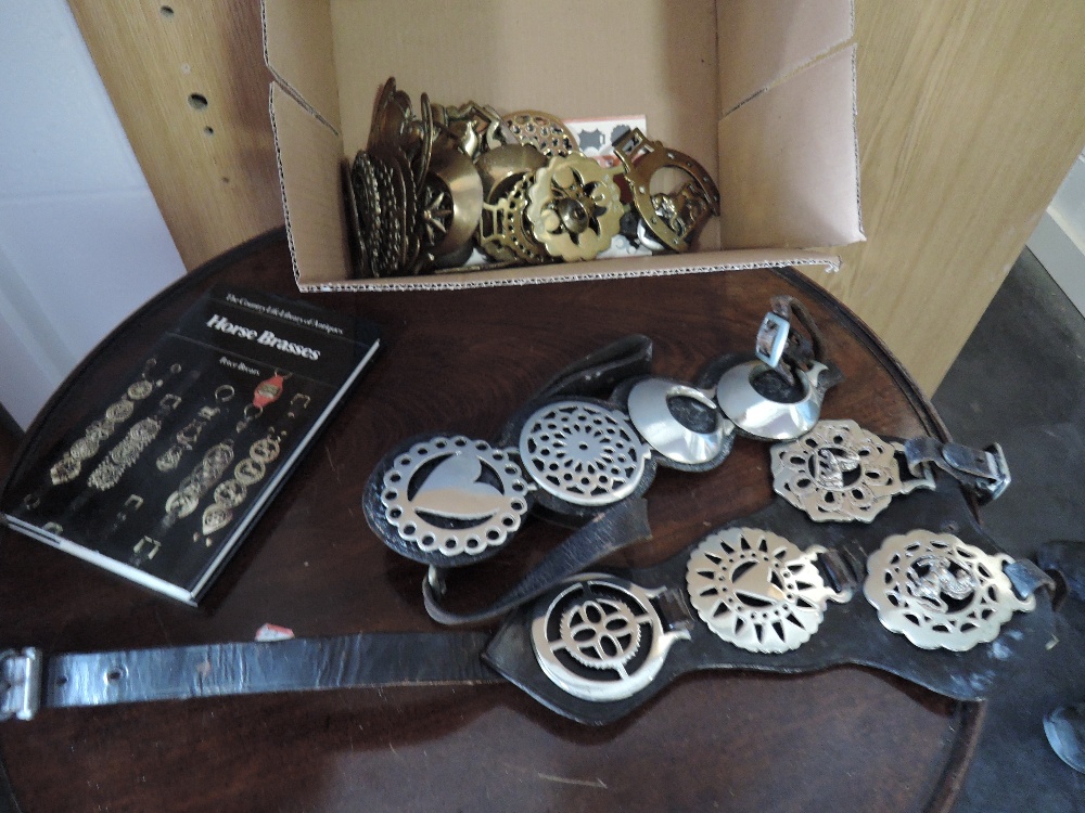 A collection of early and modern horse brasses, some on leather