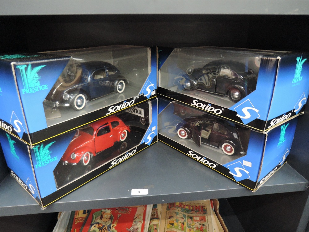 Four Solido Prestige 1:18 scale diecast Beetle cars in red, blue, purple and grey, all in window